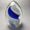 Glass ovoid paperweights often have captivating designs and inclusions, making each piece exceptional. The tranquil charm of blue and white inclusions could add a quiet, almost underwater feel to the piece, making it idyllic for display.